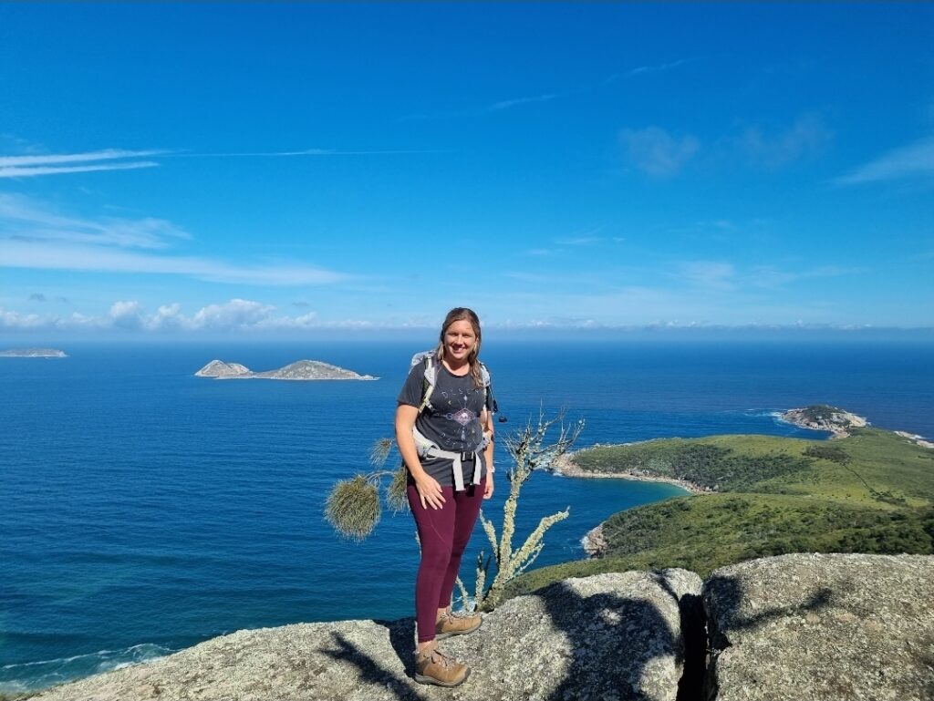 A woman in hiking clothes on top of a mountain